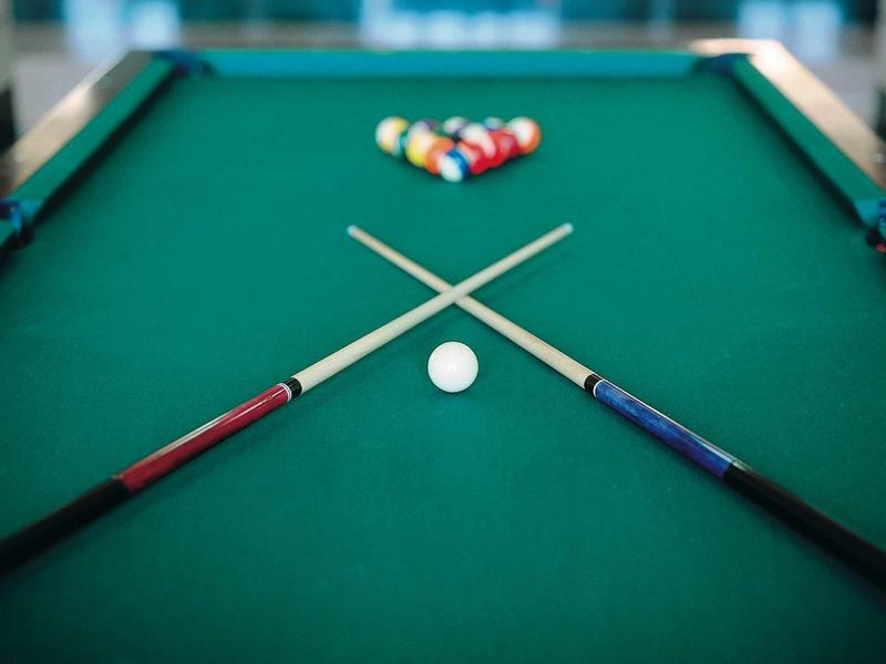 Vue d'une table de billard avec deux queues croisées et des boules colorées regroupées.