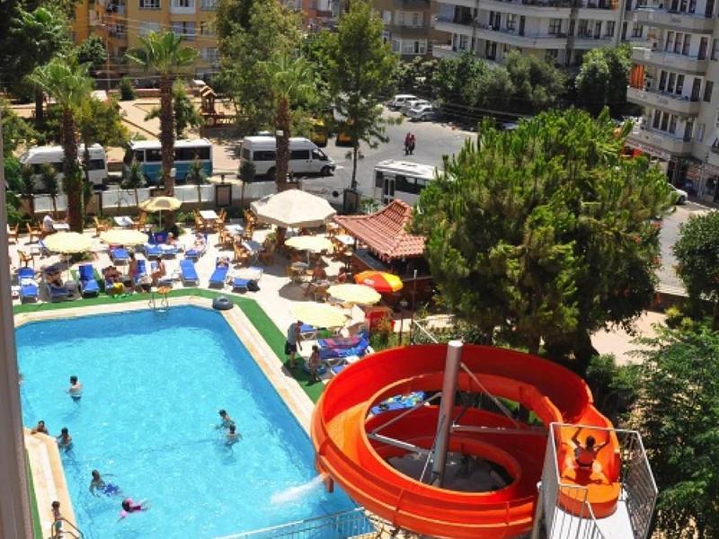 Piscine d'hôtel animée avec toboggan aquatique et transats entourés en milieu urbain ensoleillé.