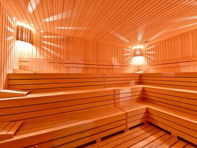 Helle Sauna mit mehrstufigen Holzbänken und warmem Licht an den Wänden.