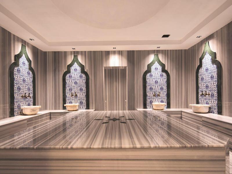 Espace de salle de bain luxueux avec éviers en marbre et fenêtres à arcades d'inspiration orientale.