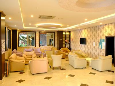 Helles, modernes Wohnzimmer mit beigen Sofas, gemusterten Wänden und warmem Deckenlicht.