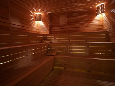 Warmer, holzverkleideter Saunaraum mit gestaffelten Sitzbänken und sanfter Beleuchtung.