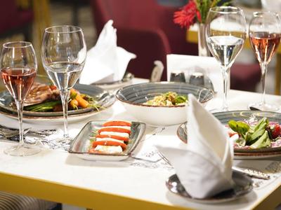 Eleganter gedeckter Esstisch mit Wein und verschiedenen Salaten in einem Restaurant.