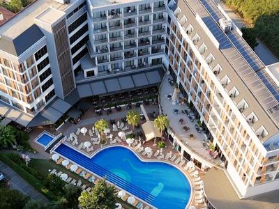 Modernes Hotel mit Außenpool und Sonnenterrasse in grüner Umgebung.