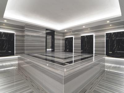 Modernes Hammam mit grauem und schwarzem Marmor, sanfter Beleuchtung und Wasserbecken.