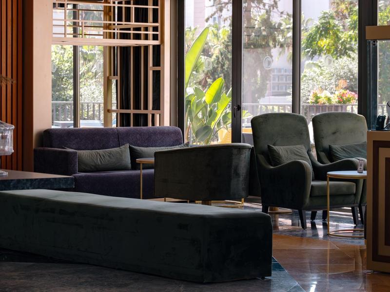 Modern eingerichteter Sitzbereich mit Sofas und Sesseln vor großen Fenstern in einem Hotel