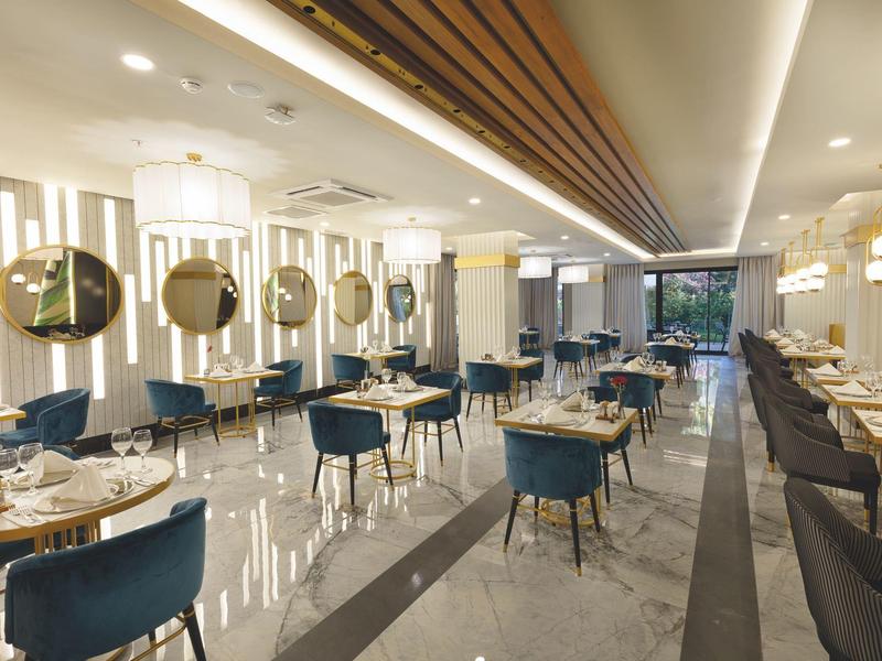 Modernes Restaurant mit blauen Stühlen, runden Spiegeln und eleganten Pendelleuchten.