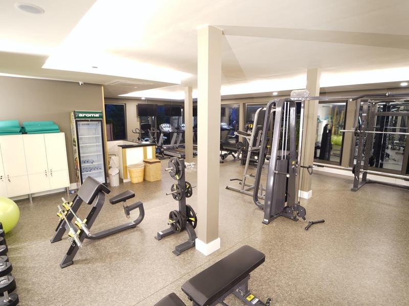 Moderner Fitnessraum mit verschiedenen Trainingsgeräten und Hanteln.