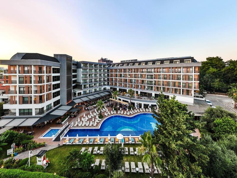 Großes Hotel mit mehreren Etagen und einem großen Poolbereich mit Liegen im Freien.