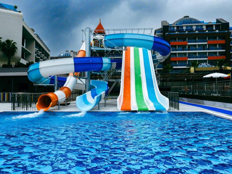 Wasserpark mit bunten Wasserrutschen und klarem blauen Pool unter bewölktem Himmel.