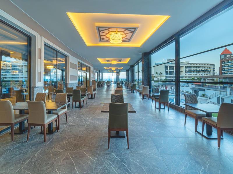 Modernes, offenes Restaurant mit großen Fenstern, hellen Deckenleuchten und Blick auf den Hafen.