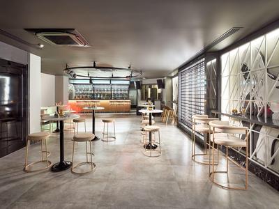 Modern, bright room with high tables and metal chairs in a hotel café.