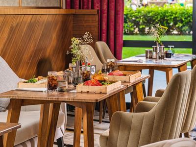 Cozy seating area with wooden tables, drinks, and a view of a green garden.