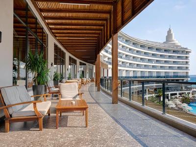 Balcony of a hotel with chairs, tables, and a view of the pool area.