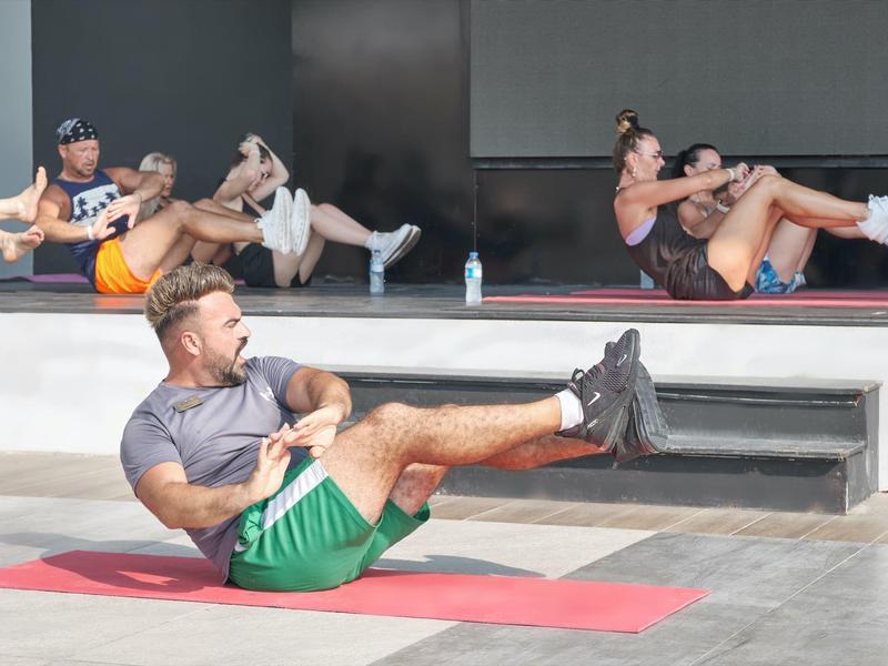Group of people doing abdominal exercises outdoors on yoga mats.