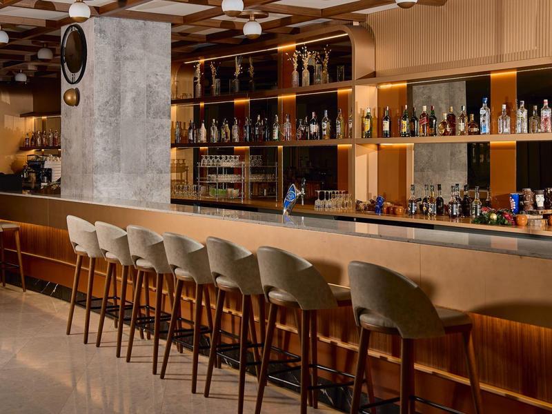 Modern hotel bar with elegant counter and comfortable gray bar stools in a warm ambiance.