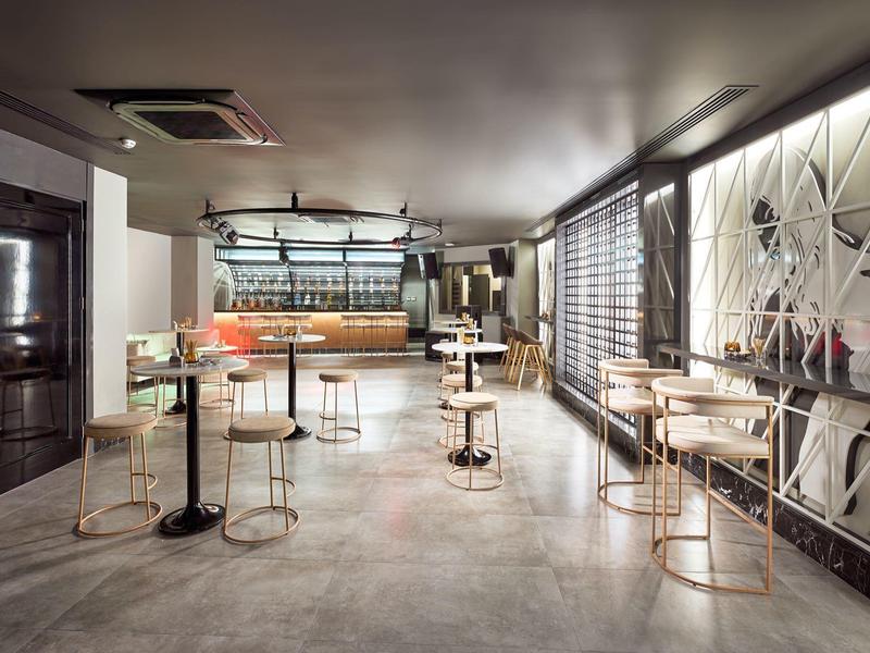 Modern, bright room with high tables and metal chairs in a hotel café.