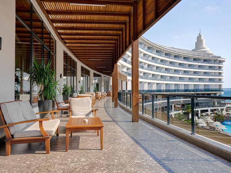 Balcony with seating area overlooking a modern hotel and outdoor pool