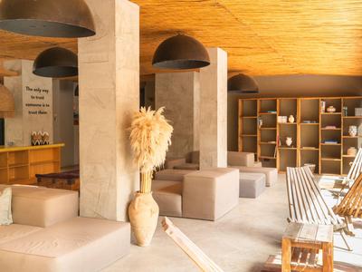 Světlý moderní hotelový lounge s dřevěným stropem, velkými lampami a světlým čalouněním.
