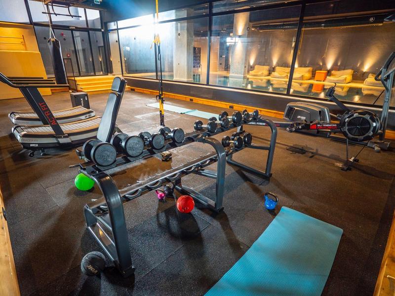 Fitnessruimte met halters, bank, yogamat en kettlebells in een modern ontwerp.