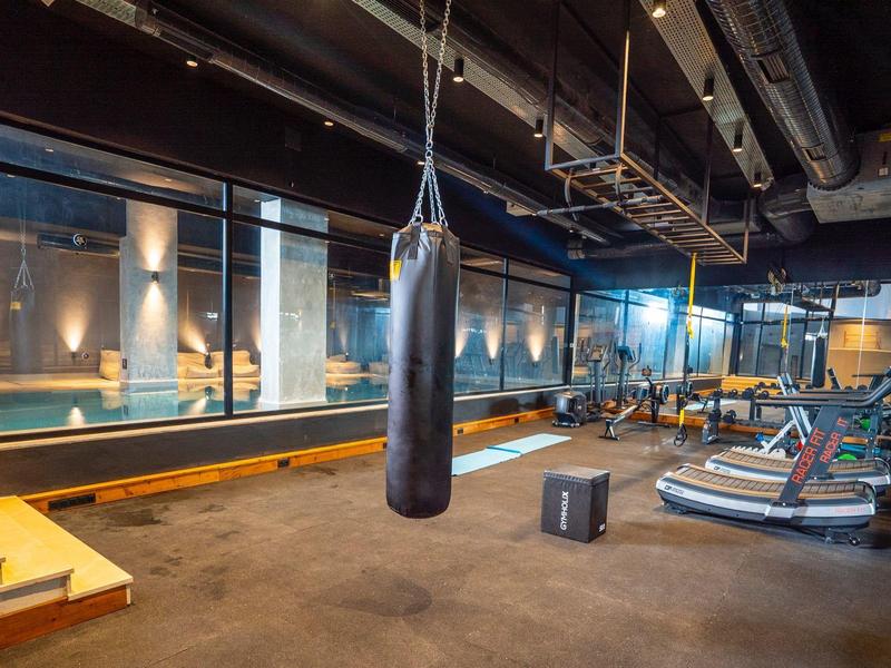 Moderne sportschool met bokszak, loopbanden en gewichten in een stijlvolle binnenruimte.