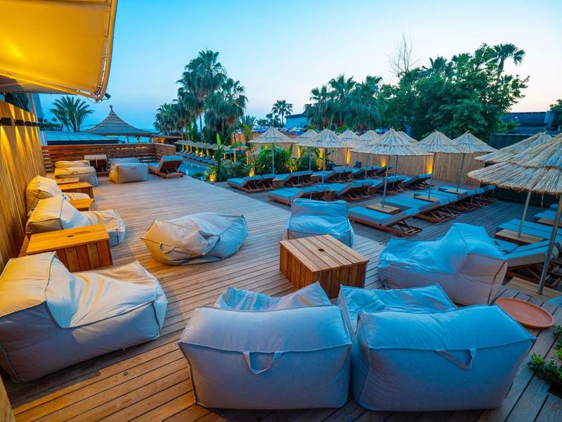 Gezellige lounge met zitzakken en ligstoelen op houten terras bij schemering.