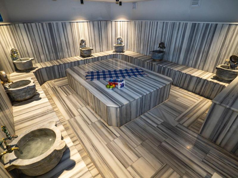 Modern Turks badhuis met marmeren bassins en centraal rustplatform in een wellnessruimte.