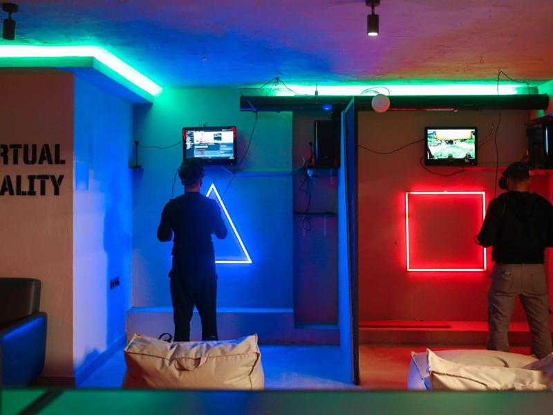 Twee mensen gebruiken virtual reality-stations met kleurrijke LED-verlichting in een donkere ruimte.