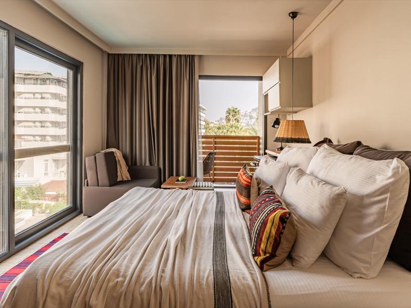 Lichte slaapkamer met groot raam, bed en gezellige zithoek met uitzicht.