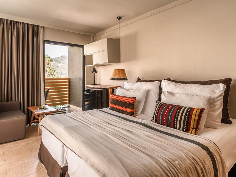 Gezellige hotelkamer met groot bed, zithoek en uitzicht op terras.