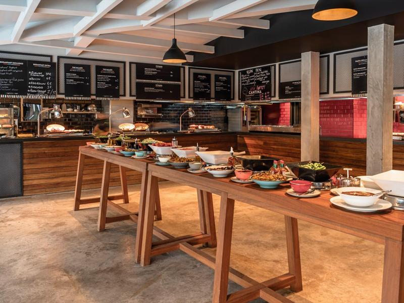 Buffet met diverse gerechten in moderne hotelkeuken met houten balies en krijtborden.