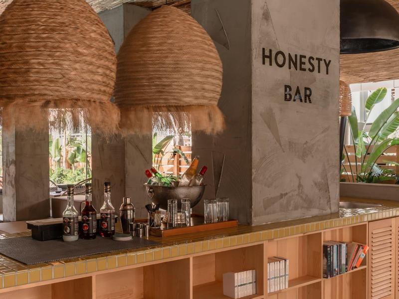 Gezellige bar met grote geweven lampenkappen en eerlijkheidsbarbord.