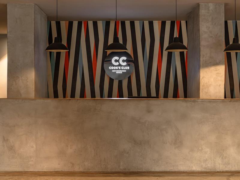 Moderne hotelreceptie met geometrische achtergrond en hanglampen.