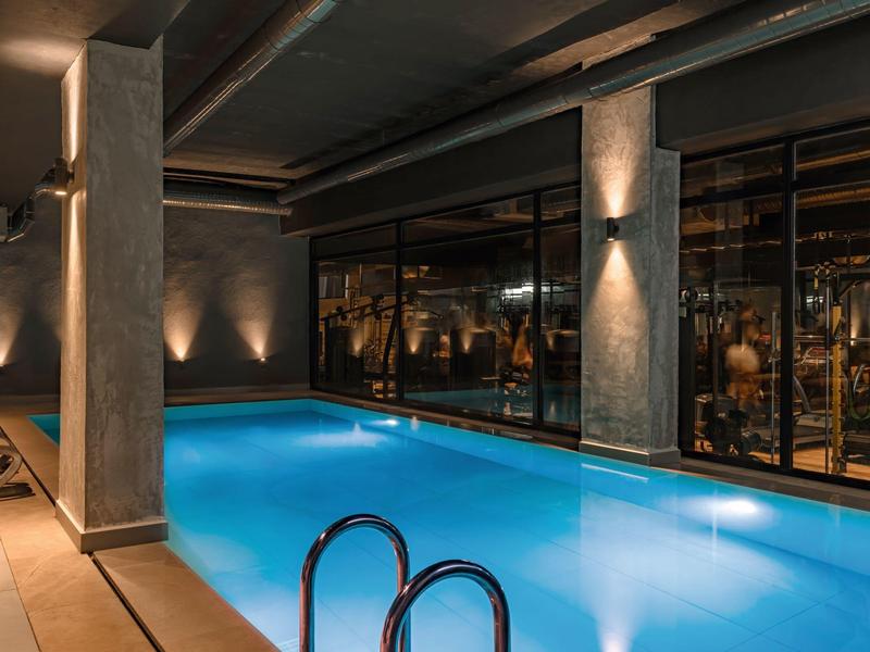 Binnenzwembad met moderne verlichting en panoramische ramen in een hotel.
