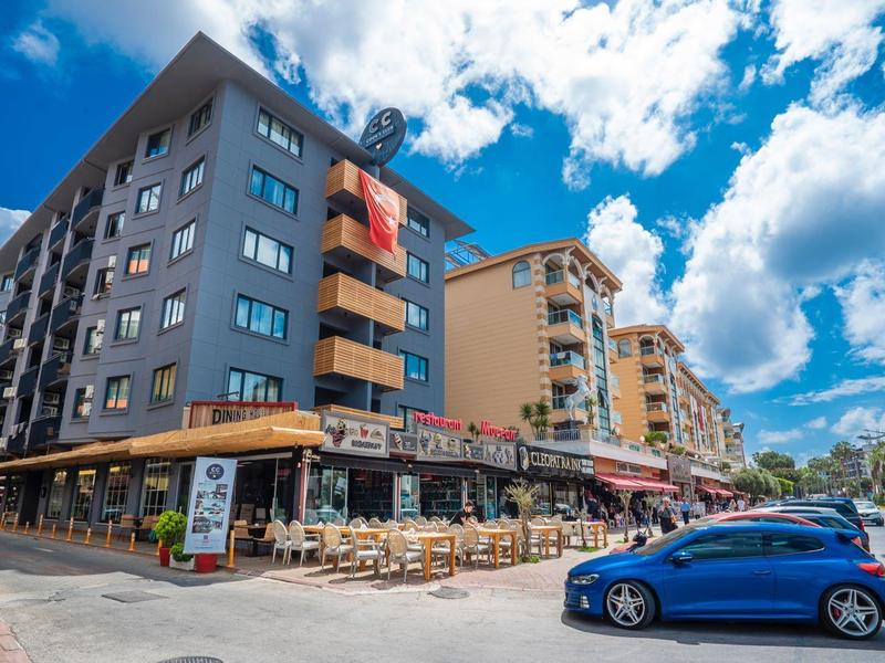 Meerdere etage hotels met buitenterras en parkeergelegenheid onder een blauwe lucht.