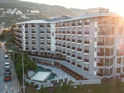 Großer moderner Wohnkomplex mit Schwimmbad, umliegenden Bergen und Nachmittagssonne.