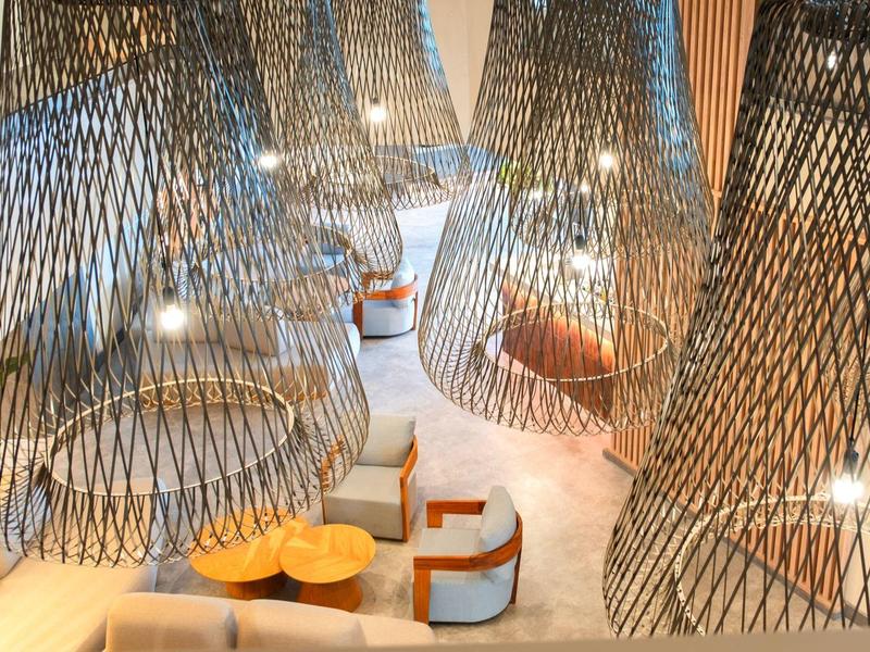 Moderne Lounge mit großen, dekorativen Hängeleuchten aus Metallgittern und gemütlichen Sitzgruppen.