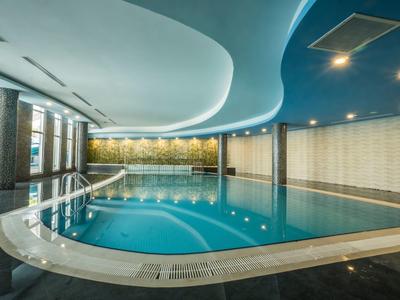 Moderner Innenpool mit blauem Wasser, geschwungener Decke und großen Fenstern an der Seite.