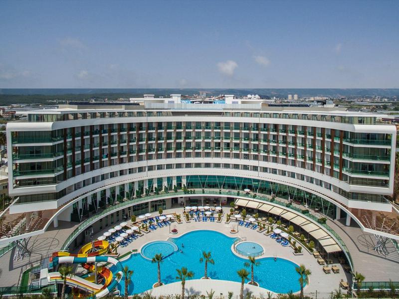 Hotel moderno con diseño curvo y gran área de piscina con toboganes acuáticos.