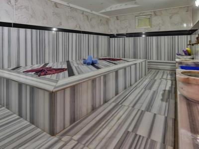 Intérieur d'un hammam avec des murs en marbre rayé et une plateforme centrale en pierre chauffée.