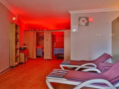 Salle de relaxation avec chaises longues et lumière rouge, zone de couchage adjacente visible.