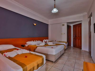 Chambre triple d'hôtel avec lits simples, couvertures colorées et sol carrelé.