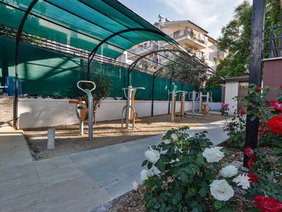 Supports à vélos couverts avec plusieurs vélos à côté d'un parterre de fleurs.