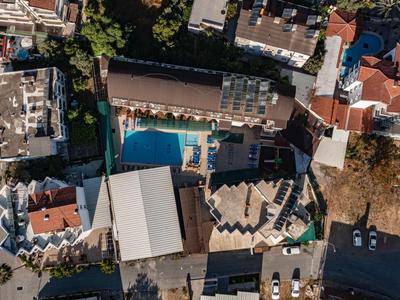 Vue aérienne d'un hôtel avec piscine, entouré de bâtiments et de parkings.