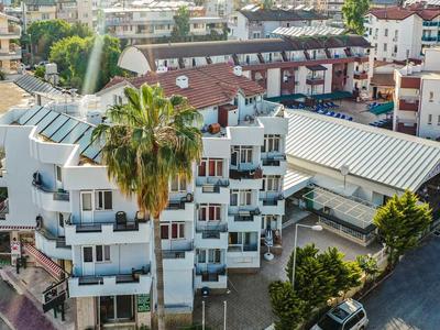 Bâtiment résidentiel à plusieurs étages avec balcons et palmiers dans un cadre urbain animé.
