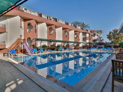 Piscine d'hôtel moderne avec toboggan et terrasse ensoleillée au coucher du soleil.
