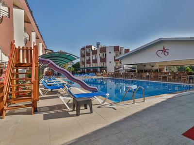 Piscine extérieure avec toboggan aquatique et transats devant un bâtiment hôtelier sous un ciel clair.