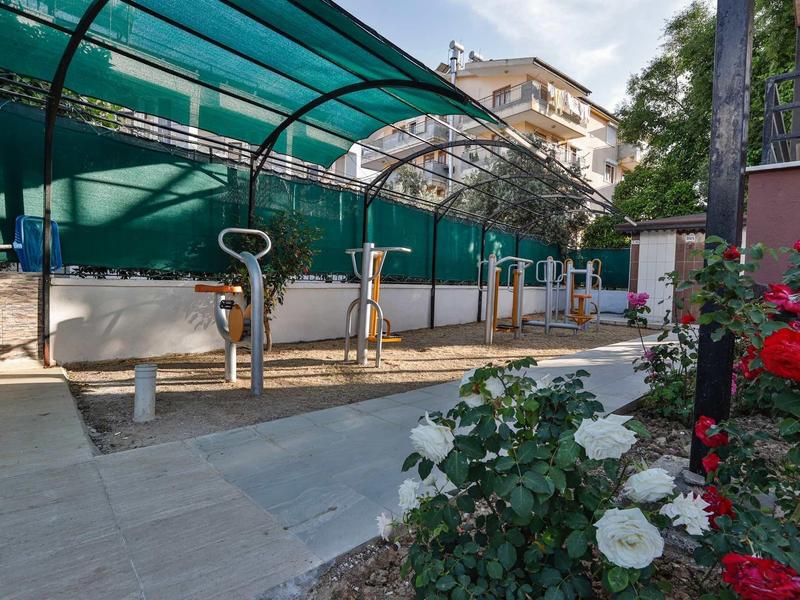 Supports à vélos couverts avec plusieurs vélos à côté d'un parterre de fleurs.