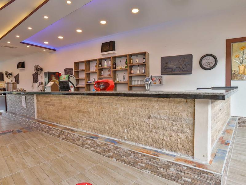 Réception d'hôtel moderne avec long comptoir, étagères et éclairage lumineux.