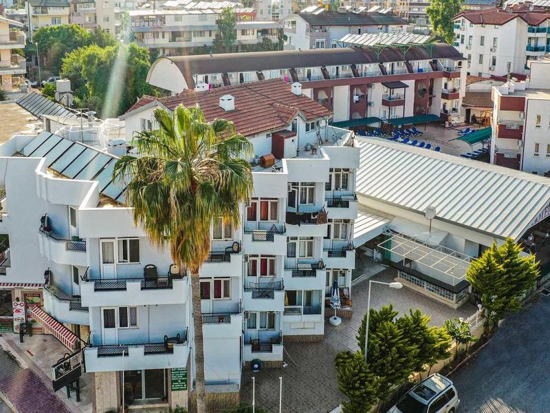 Bâtiment résidentiel à plusieurs étages avec balcons et palmiers dans un cadre urbain animé.